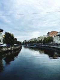 Buildings by river against sky