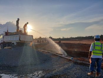 Rear view of people working on bridge against sky