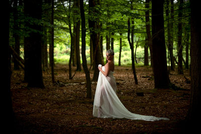 Woman standing on tree trunk in forest