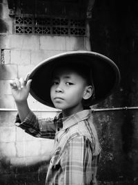 Rear view of man standing against wall, boy wearing a bamboo hat