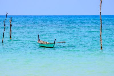 Scenic view of empty boat moored by a post in turquoise sea