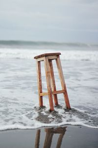 Wooden posts on beach against sky during winter