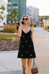 Young happy woman is walking around the city, talking on a mobile phone.