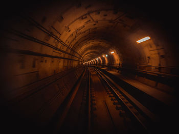 Railroad tracks in illuminated tunnel