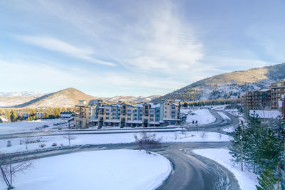 Snow covered road by buildings against sky