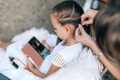 High angle view of woman tying daughter hair