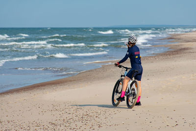 Side view of man riding bicycle on beach