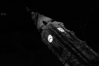 Low angle view of clock tower at night