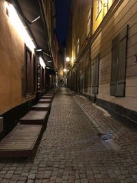 Empty alley amidst buildings in city at night