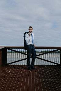 Man standing on bridge against sea