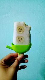 Close-up of person holding ice cream against wall