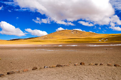 Scenic view of landscape by mountain against cloudy sky