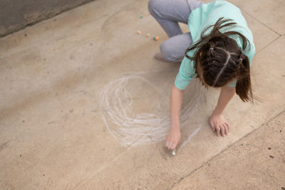 Girl draws with colorful crayons on pavement. children's drawings with chalk on wall. creative kid.