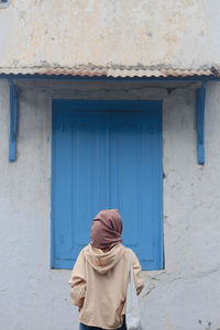 Portrait of young woman standing against wall