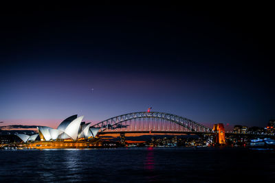 Illuminated bridge over river at night