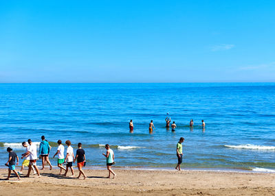 People on shore against blue sky