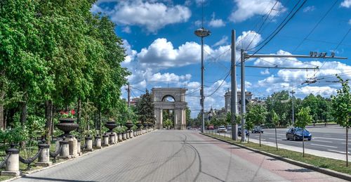 Street amidst trees against sky in city