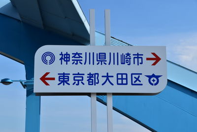 Low angle view of road sign against blue sky