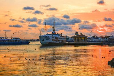 Boats moored at harbor during sunset