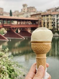 Close-up of hand holding ice cream cone overlooking ponte degli alpini in bassano del grappa, italy 