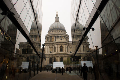 People walking in front of buildings against sky in city