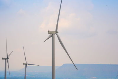 Wind turbines on landscape against sky