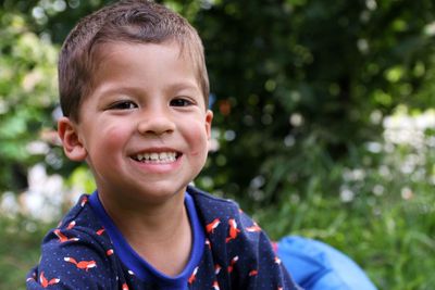 Portrait of boy smiling while sitting in yard