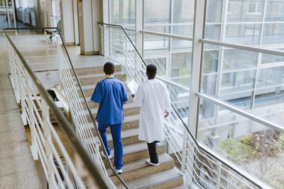 High angle view of male doctor and nurse discussing while moving up on staircase in hospital