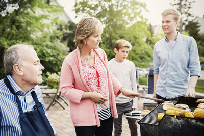 Grandparents and children barbecuing at yard
