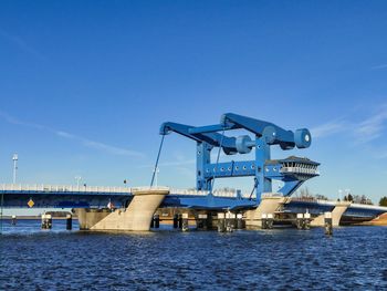 Low angle view of bridge over river against blue sky