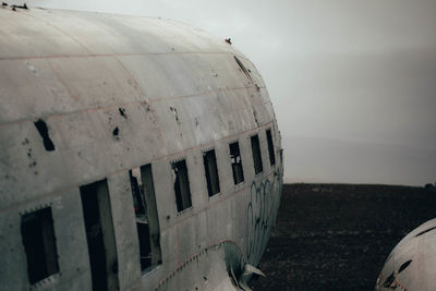 Abandoned airplane on beach against sky