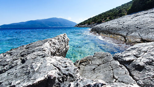 Rocks by sea against blue sky