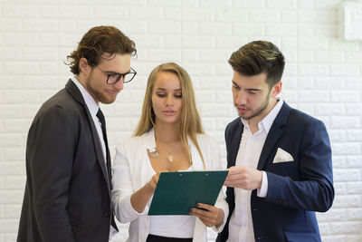 Business colleagues discussing over document while standing in office