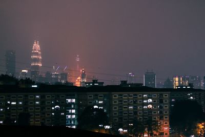 Illuminated buildings in city against sky at night