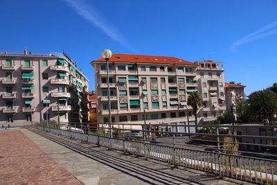 Railroad tracks by buildings against clear blue sky