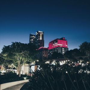 Illuminated city against clear blue sky at night