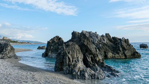 Rock formation on beach against sky