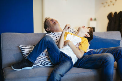 Carefree father and son having fun on couch at home