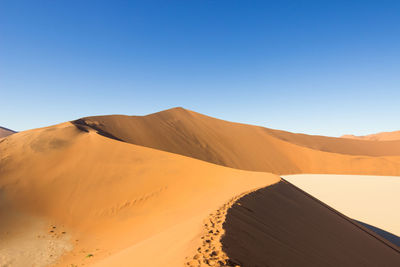 Scenic view of desert against clear blue sky