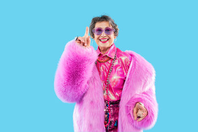 Portrait of young woman standing against blue background