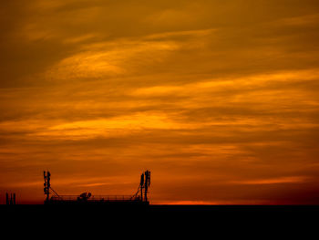 Silhouette of crane against dramatic sky during sunset
