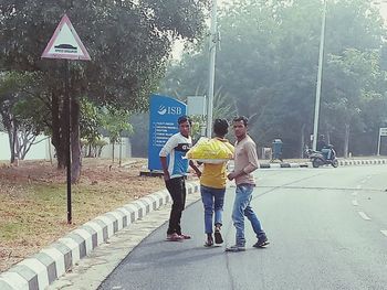 Rear view of people walking on road in city