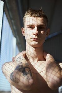 Portrait of young man standing by window