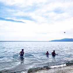 People in sea against sky