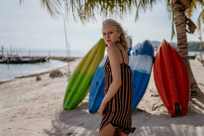 Fashion girl in a striped dress on the beach near the colored boards