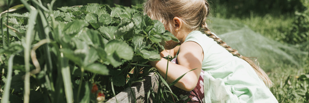 REAR VIEW OF WOMAN STANDING ON PLANTS