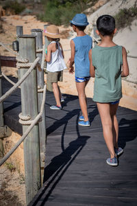 Rear view of siblings walking on boardwalk