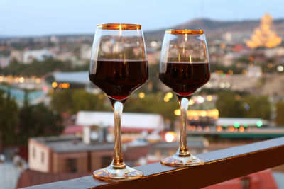 Two wine glasses on the balcony with blurry evening city view in background