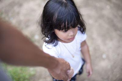 High angle view of cropped hand holding girl