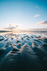 Surface level of beach against sky during sunset